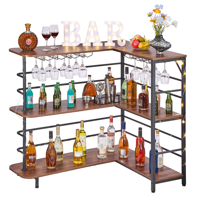 Étagère de bar en forme de L à 3 niveaux avec structure métallique et surfaces en panneaux de particules, porte-verres intégré et éclairage DEL d'ambiance. Finition noyer. Présentoir à spiritueux idéal pour sous-sol, cuisine, salon ou pub.