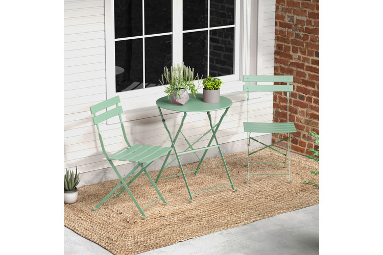 Small front porch idea with a mint green bistro set with two small potted plants on the table and a jute rug underneath.