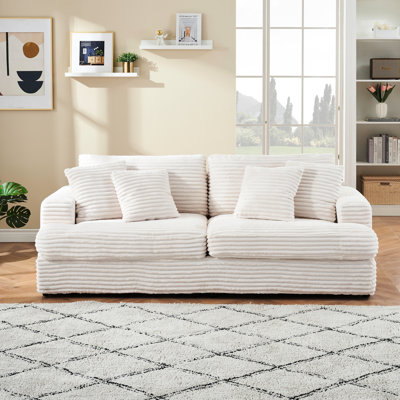 Canapé 3 places spacieux et confortable en velours côtelé avec quatre coussins décoratifs, parfait pour se détendre dans un salon moderne