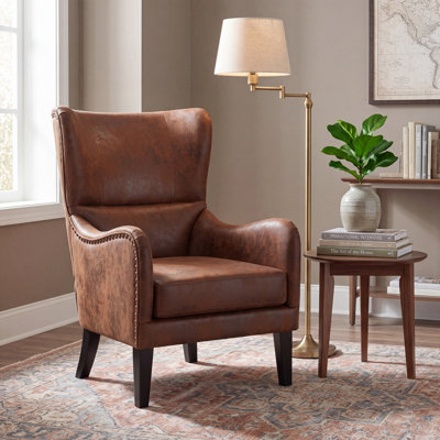 Fauteuil à oreilles en similicuir vieilli avec garniture cloutée