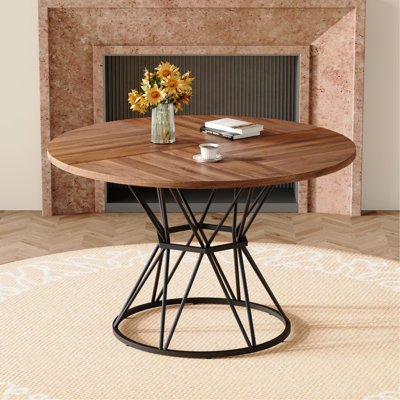 Une table de salle à manger circulaire d'un diamètre de 47,3 pouces, comprenant 4 plateaux de table en bois aggloméré à grain de bois de noyer, des supports en métal en forme de sablier noir et une table de salle à manger de style industriel moderne pour 4 à 6 personnes.