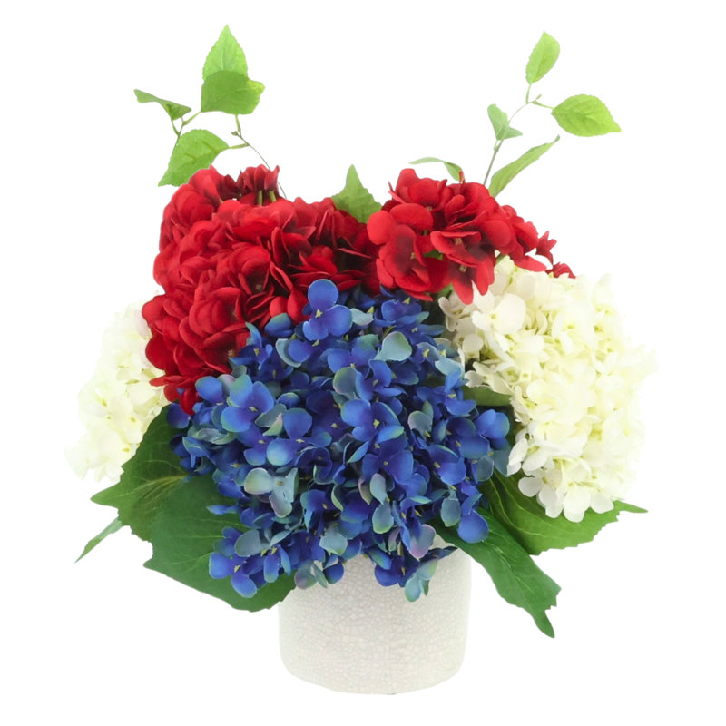 Arrangement d'hortensias rouges, blancs et bleus dans un pot en céramique