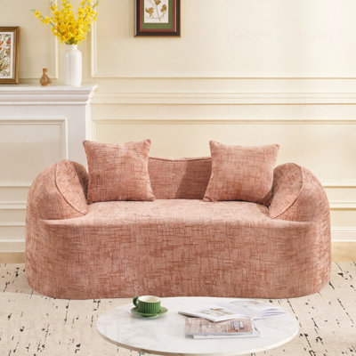 Pink Curved two - person compress sofa. It has armrests on both sides, comes with two pillows, is  for small - sized apartments