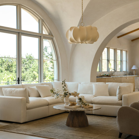 Living room with white sectional sofa, coffee table, and arched window.