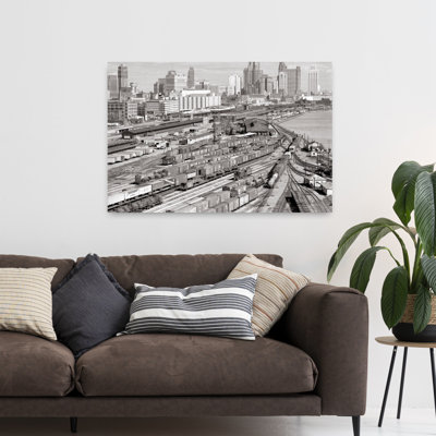 1960s INDUSTRIAL FREIGHT TRUCKING AND RAILROAD BOXCAR TRAIN YARDS ALONG RIVER CITY BUILDINGS SKYLINE IN B G DETROIT MICHIGAN USA by H. Armstrong Roberts - Wrapped Canvas Print
