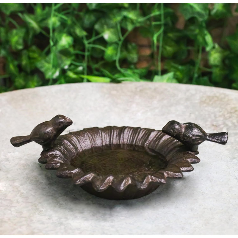 Petits tourtereaux rustiques en fonte perchés sur un bain de jardin