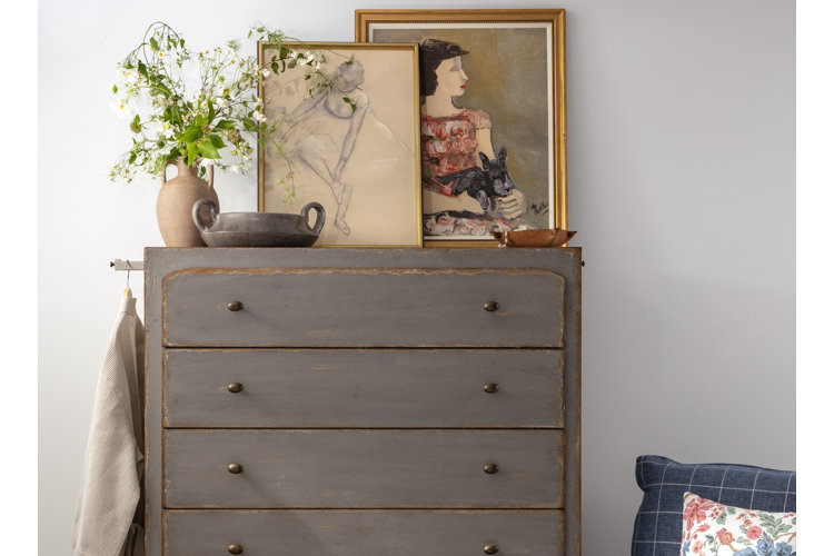 Distressed painted dresser with two vintage art prints and pottery vases on the dresser top.
