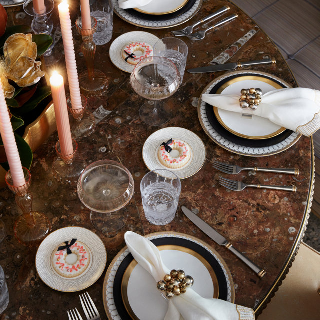 Overhead view of place settings with plates, silverware, glasses, candles, and donut cookies.