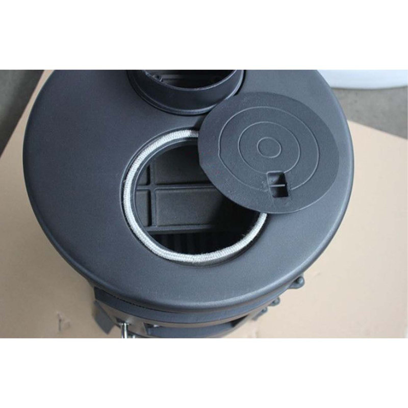 Small cylindrical cast iron wood-burning fireplace