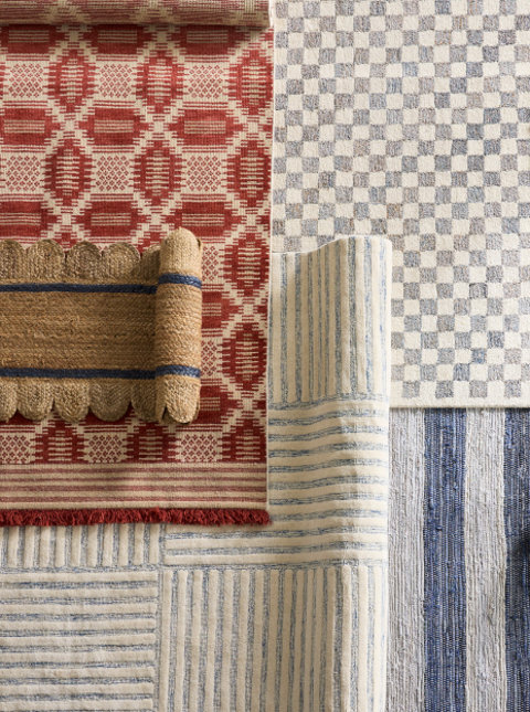 Overhead view of rolled patterned rugs in red, brown, and blue.