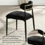 Chaise de salle à manger moderne et minimaliste, revêtue de tissu noir, avec dossier cylindrique incurvé et pieds en métal.