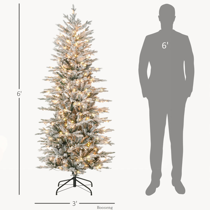 Arbre de Noël floqué avec branches enneigées et lumières jaunes chaudes