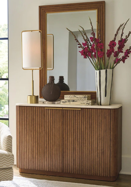 Wood sideboard with a white marble top and a mirror.