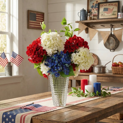 Arrangement d'hortensias rouges, blancs et bleus dans un vase en verre