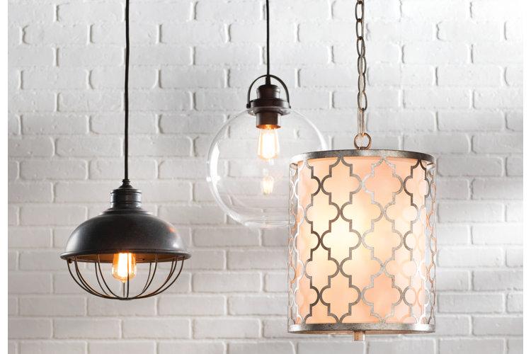three lit up pendant lights hanging in front of a white brick wall