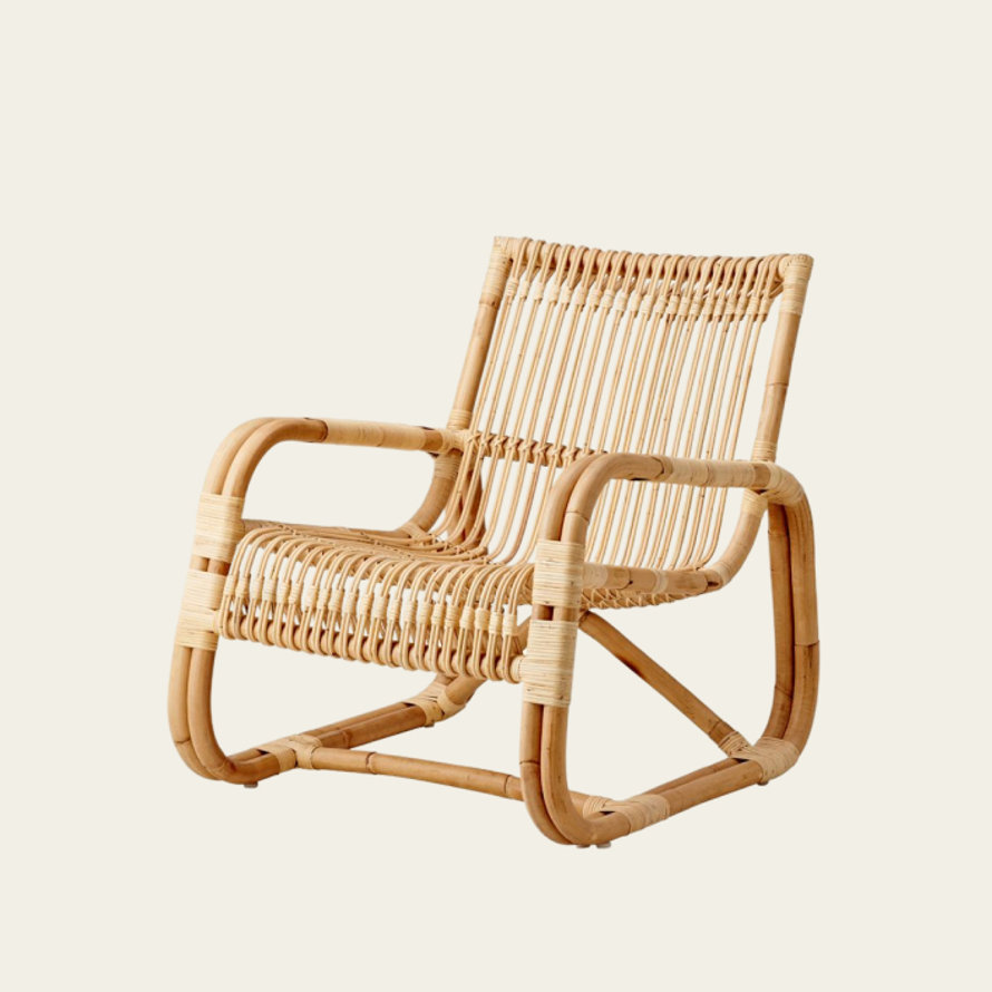 Modern natural rattan lounge chair with a low-profile curved frame and woven seat and backrest.