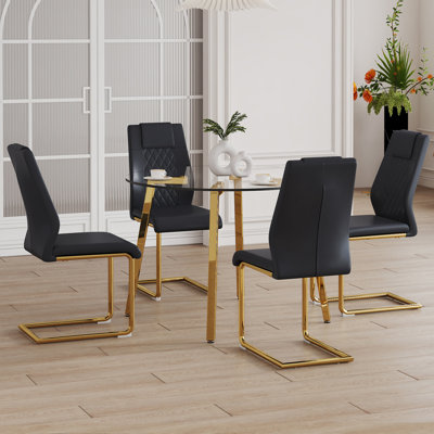 Ensemble de table et de chaises. Une table ronde en verre trempé transparent de style minimaliste moderne avec des pieds en métal. De plus, elle est dotée de chaises noires avec un dossier haut en cuir de polyuréthane rembourré et des pieds dorés en