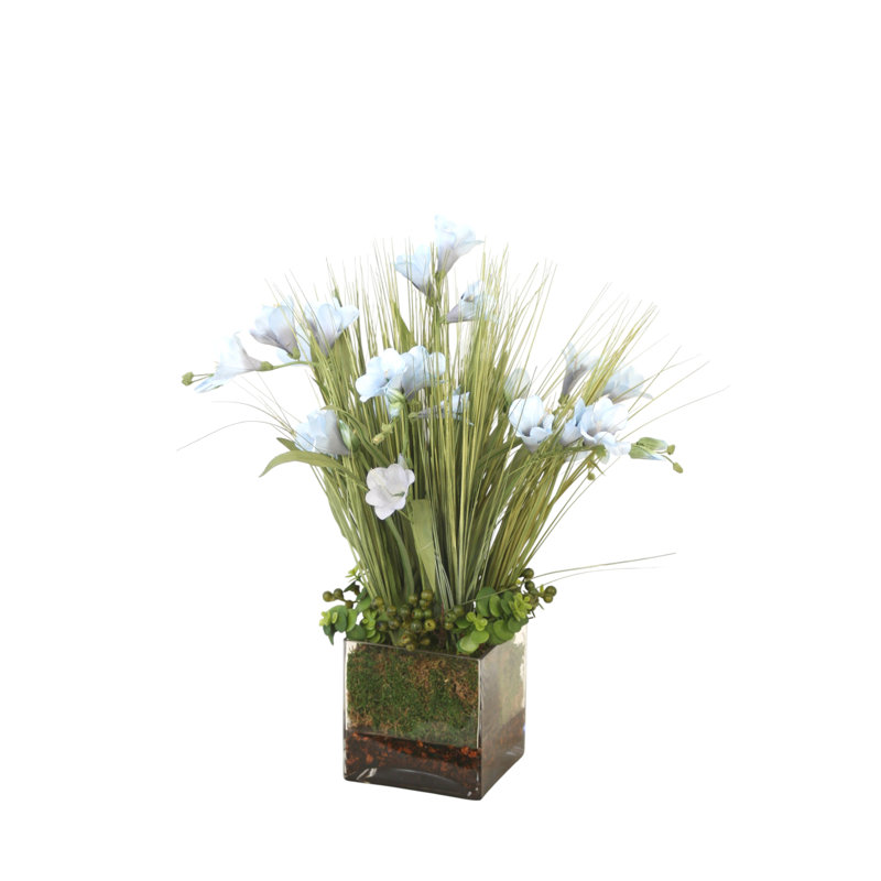 Freesia bleu glacier mélangé avec de l'herbe et des baies dans un récipient en verre carré
