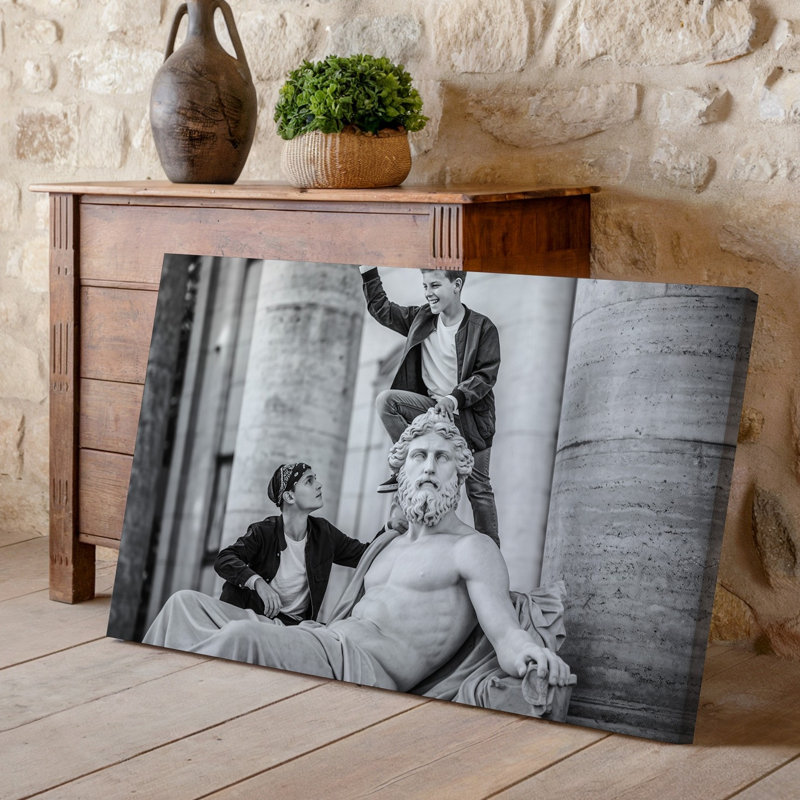 Toile, une scène dynamique en noir et blanc capture deux garçons qui interagissent avec une grande statue classique