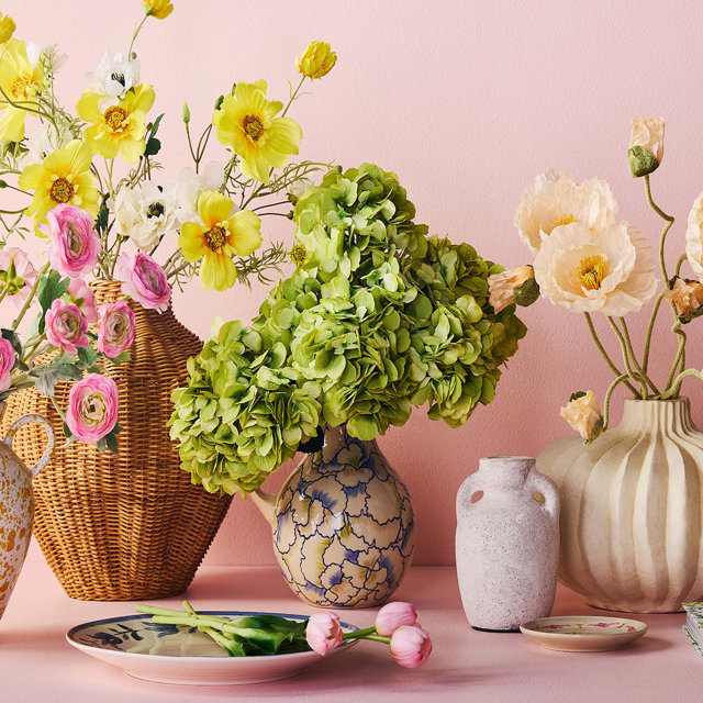An assortment of faux florals in pastel colors against a pink background.