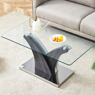 Table basse rectangulaire en verre avec pattes stables et design artistique dans les tons gris et blanc. Élégant plateau transparent.