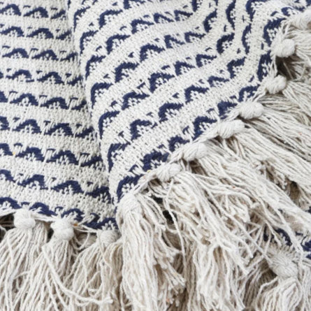 Close-up of a fringed throw blanket with a blue and white patterned design.