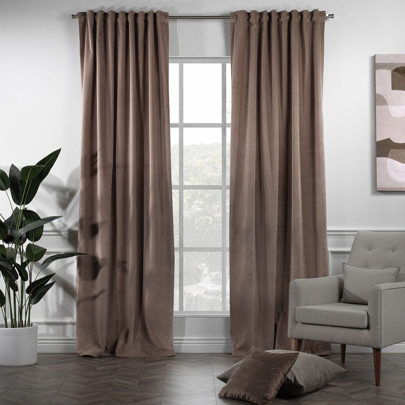 Brown matte velvet curtain panels hanging on a rod in a living room.