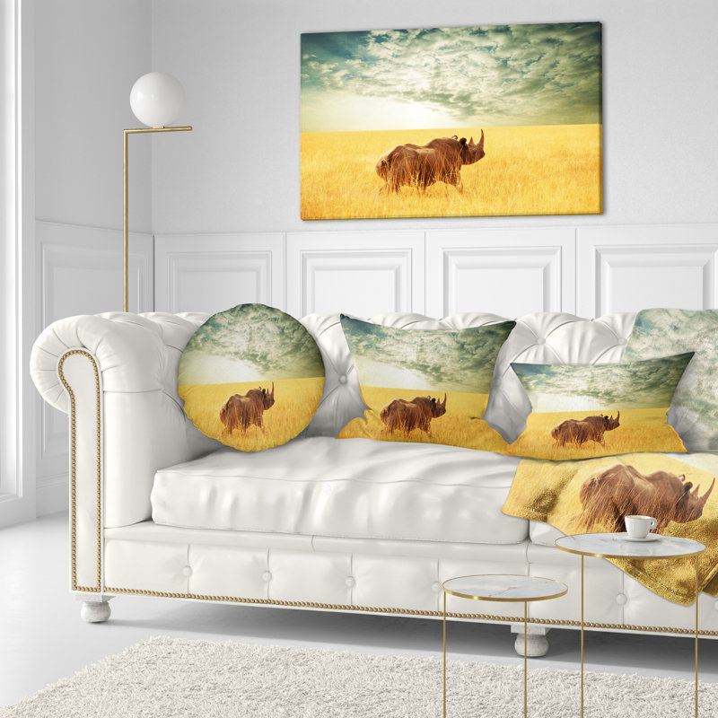 Coussin rhinocéros africain dans une prairie sous un ciel nuageux