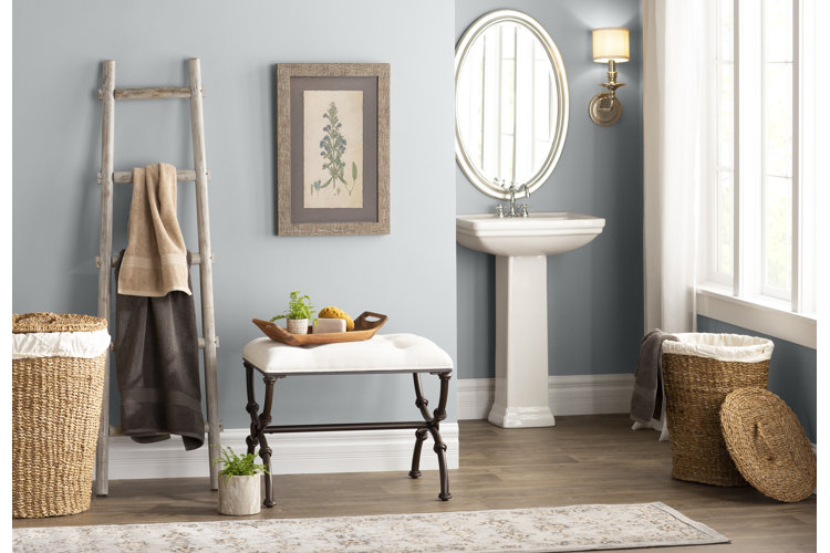 modern farmhouse bathroom with a towel ladder, bench, and beige floral bath runner rug