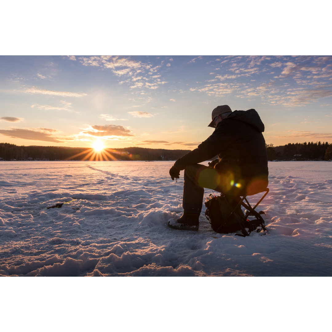 Leinwandbild Eisfischen auf einem See in Norwegen bei Sonnenuntergang