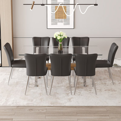 Ensemble de table et de chaises. Ensemble de salle à manger élégant en verre trempé transparent - 71 po x 35,4 po avec chaises en polyuréthane avec un motif à rayures verticales sur le dossier. Traverses en bois aggloméré, pieds en métal argenté.