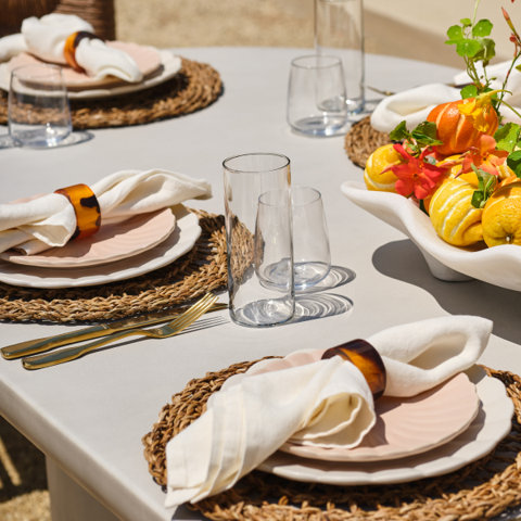 A table setting with plates, glasses, and a fruit centerpiece.