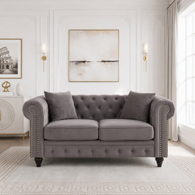 Canapé Chesterfield 2 places en velours doux, orné de boutons, d'accoudoirs arrondis et de pieds en bois.