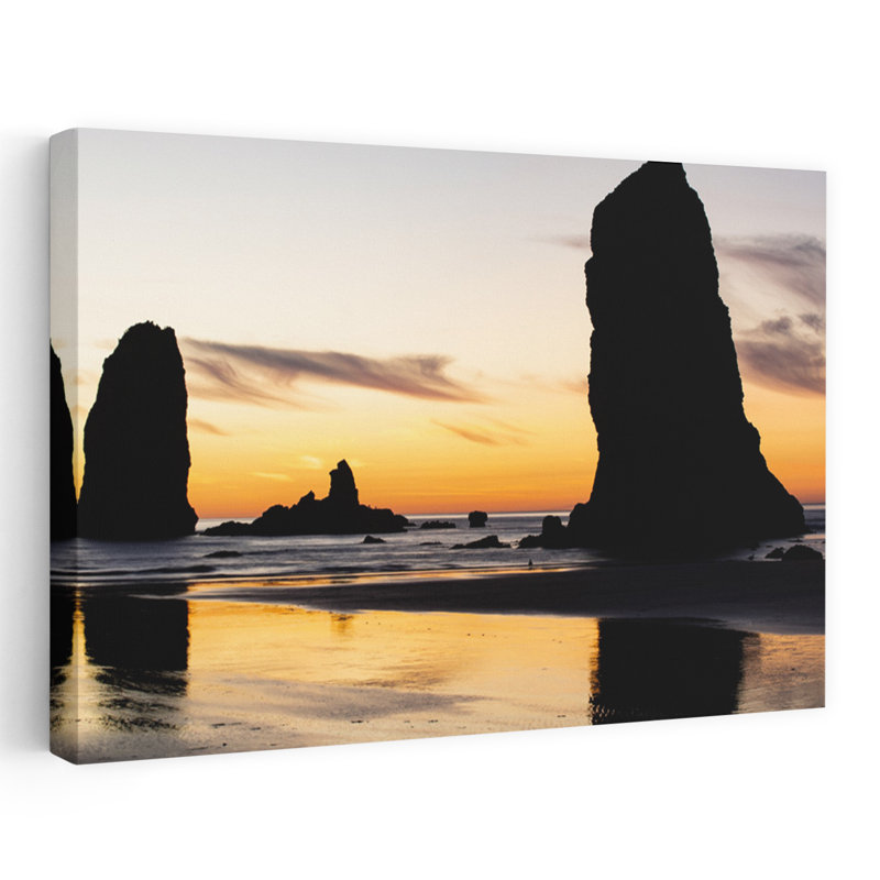 Silhouettes Of Rock Formations At Sunset At Cannon Beach Oregon USA by Dan Merkel - Wrapped Canvas Print