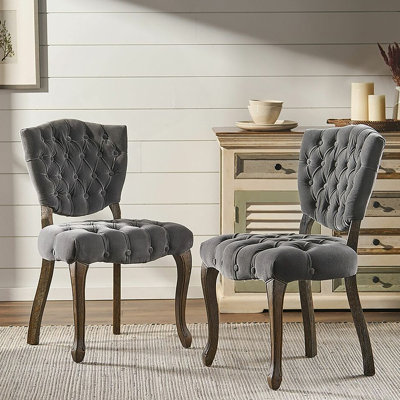 Ensemble de deux chaises capitonnées d'inspiration européenne avec pieds sculptés à la main et revêtement capitonné pour des solutions d'assise polyvalentes.