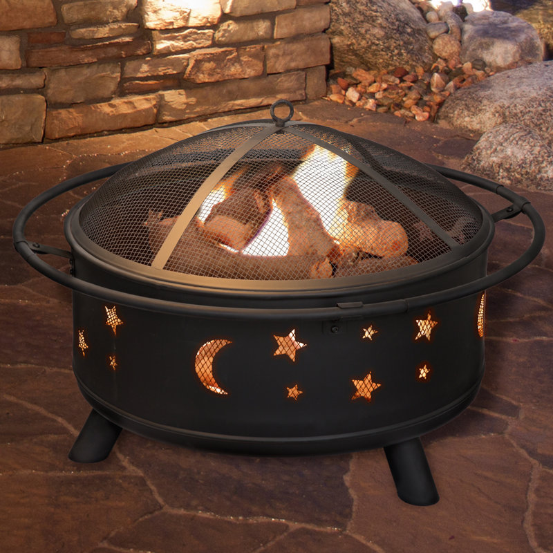 A round black fire pit with star and moon cutouts on the side