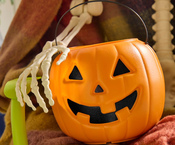 vintage halloween aesthetic with a classic jac o lantern plastic candy button being held by a skeleton arm