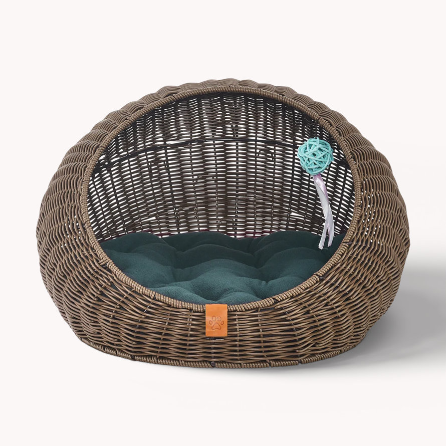 Wicker pet cave bed with green cushion and toy