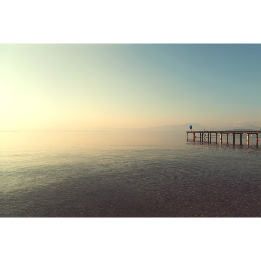 Leinwandbild Man On A Boardwalk Observing Calm Lake Scenary At Sunset