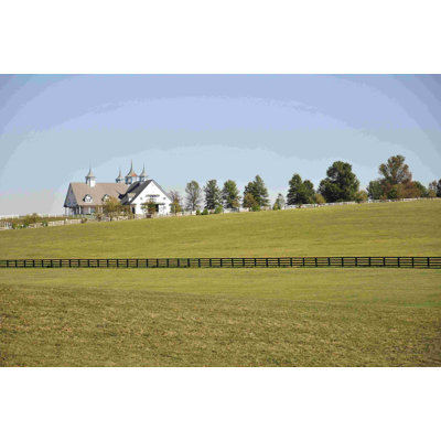 Grand champ vert avec ferme et clôture noire - photographie sur toile tendue