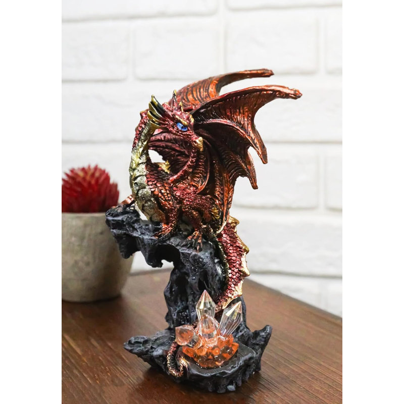 Figurine fantaisie dragon volcanique perché sur un rocher avec des cristaux
