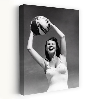 1940S, femme souriante en maillot de bain blanc tenant un ballon de plage au-dessus de sa tête