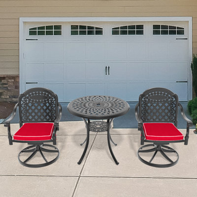 Ensemble bistro 3 pièces comprenant une table ronde extérieure de 78 cm (30,71 po) avec trou pour parasol et 2 chaises pivotantes avec coussins rouges.