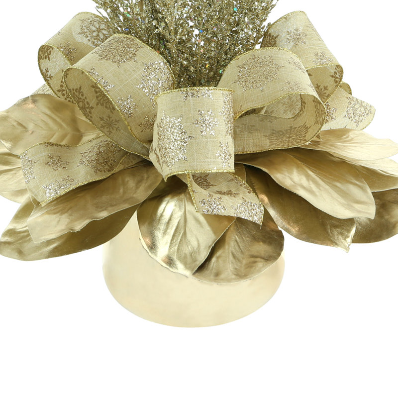 Holiday Arrangement With Magnolia Leaves, Sparkly Branches And Bows In A Glass Vase