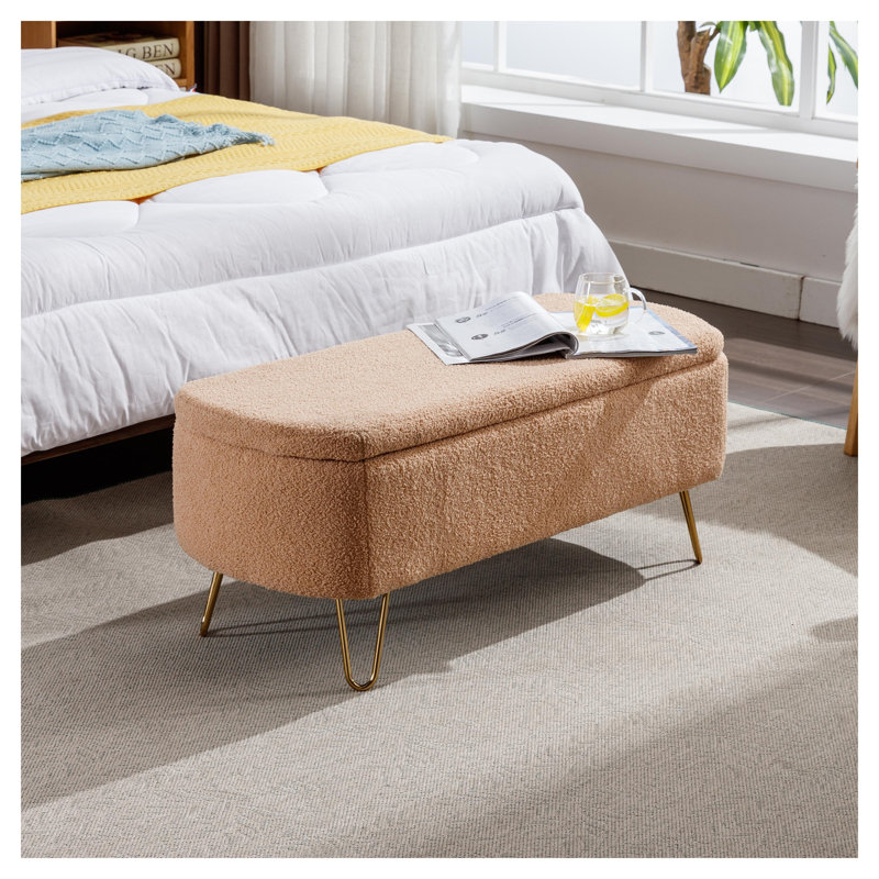 Pouf de rangement en fausse fourrure camel avec pattes dorées, idéal pour une chambre, au pied du lit ou dans une entrée.