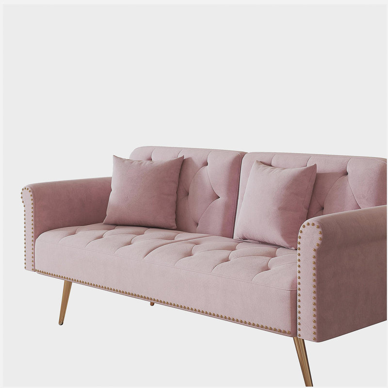 A 69.7 inch Long Sofa Bed covered in Pink Velvet Fabric, equipped with nail head decorations and matching throw pillows