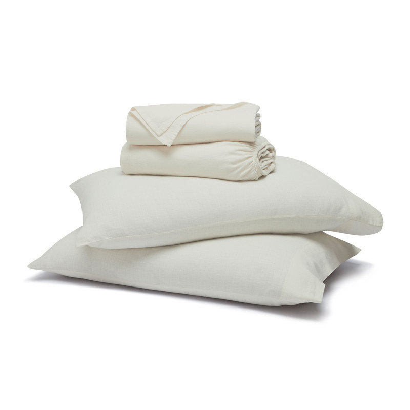 Off-white sheet set including two pillows and folded flat and fitted sheets