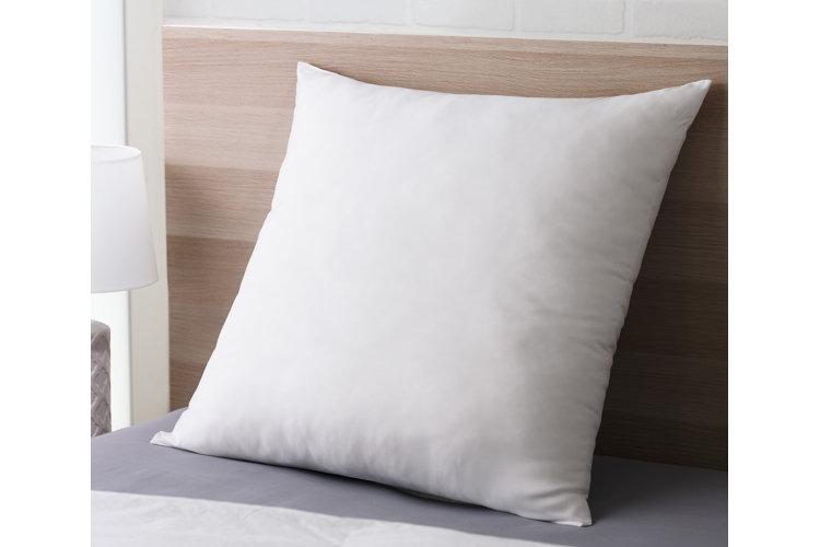  White euro-style pillow leaning up against a bed headboard.