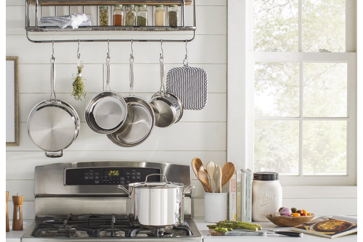 silver pots and pans hanging above a stove displaying different skillet sizes and skillet dimensions