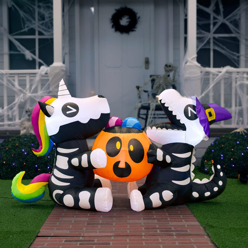 Squelette assis licorne et dinosaure tenant une citrouille d'Halloween gonflable